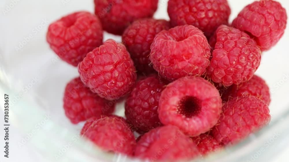 Turning fresh red raspberries on plate, close up, slow motion Turning fresh red raspberries on plate, close up, slow motion