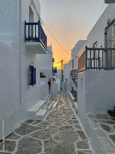 Typical street of greek traditional village with white walls and colorful doors, windows and balconies Sunset on Mykonos Island, Greece, Europe photo