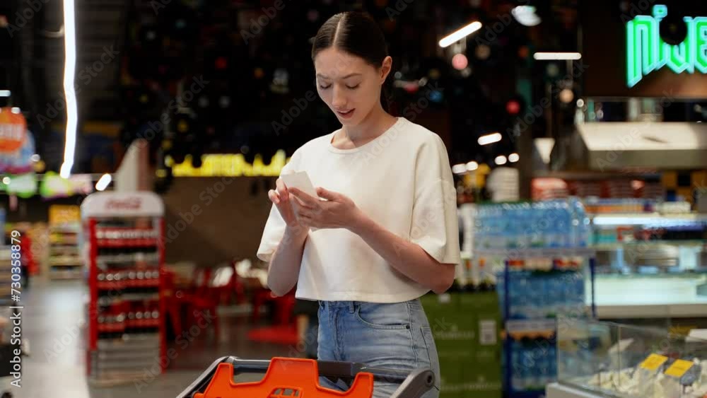 Woman in a supermarket checks shopping receipt and grocery store cart Woman in a supermarket checks shopping receipt and grocery store cart
