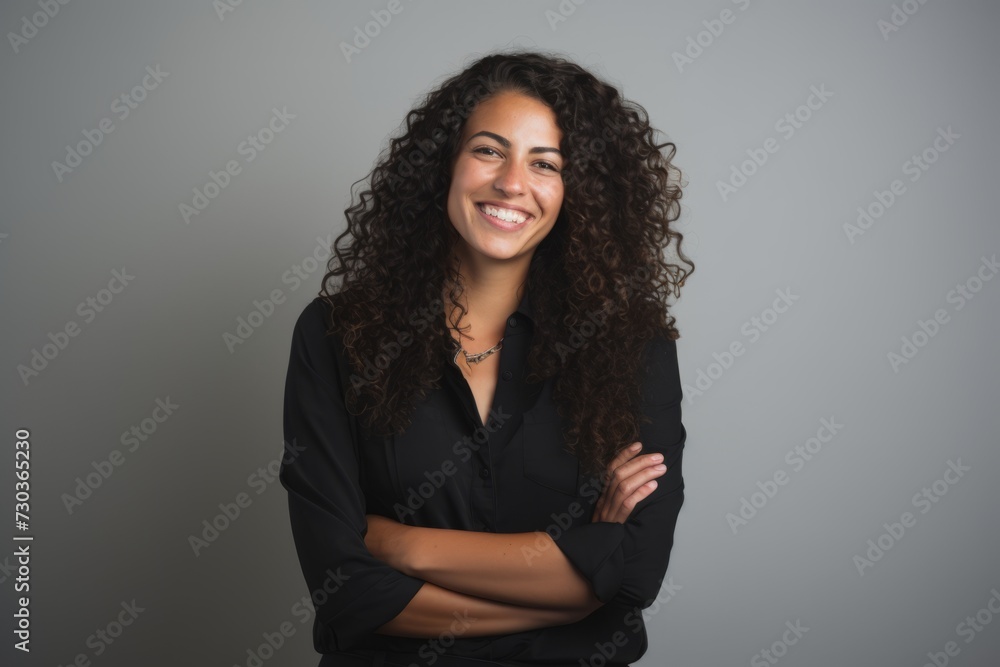 Portrait of a smiling young businesswoman with arms crossed against grey background Portrait of a smiling young businesswoman with arms crossed against grey background