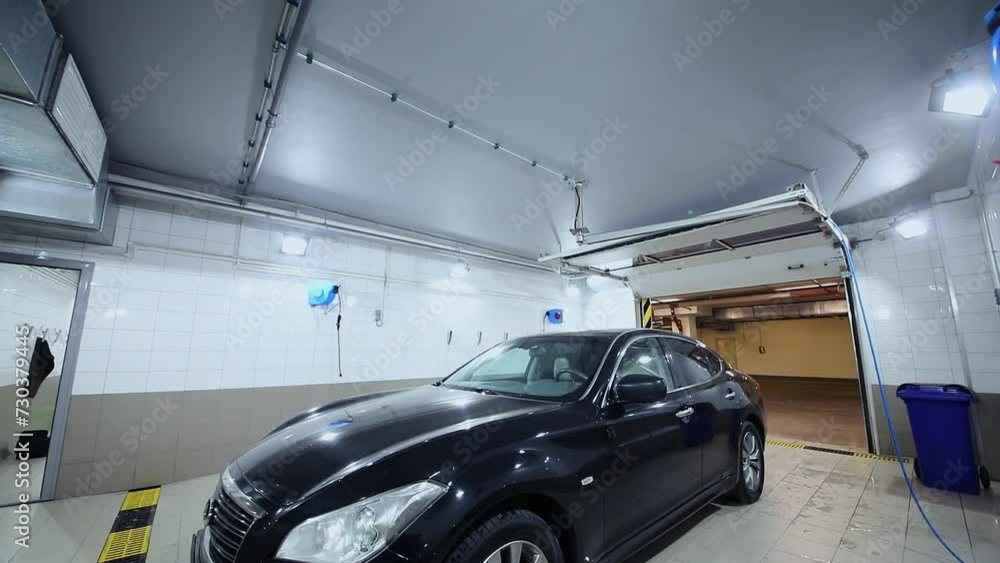Black vehicle is in washing box of car service station Black vehicle is in washing box of car service station