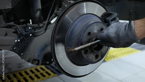 Man in gloves scours car wheel disk by metal brush and sprays solution. Slow motion photo