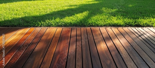 Deck boards made of Ipe hardwood with evergreen grass alongside the exotic wood floor planks. photo