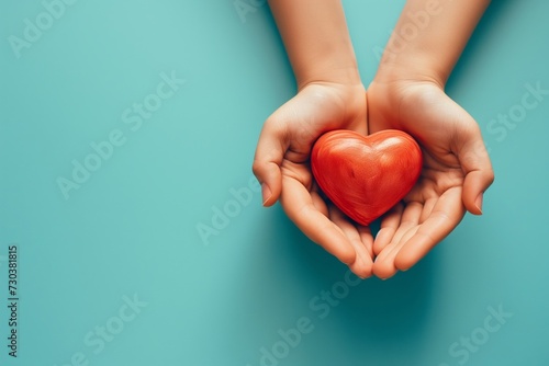Hands Holding a red heart on blue background with copy space