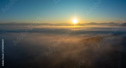 Aerial view amazing the sea of mist at beautiful sunrise...slow floating fog blowing cover on the top of mountain look like as a sea of mist. ..white cloud in blue sky over the perfect forest.