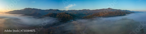Aerial view amazing the sea of mist at beautiful sunrise...slow floating fog blowing cover on the top of mountain look like as a sea of mist. ..white cloud in blue sky over the perfect forest.