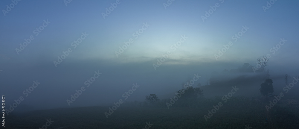 Fototapeta premium aerial view a sea of white mist envelops the mountain peak, slowly flowing down from the mountain peak...The mist poured down from the mountains in the morning...the sea of mist background.