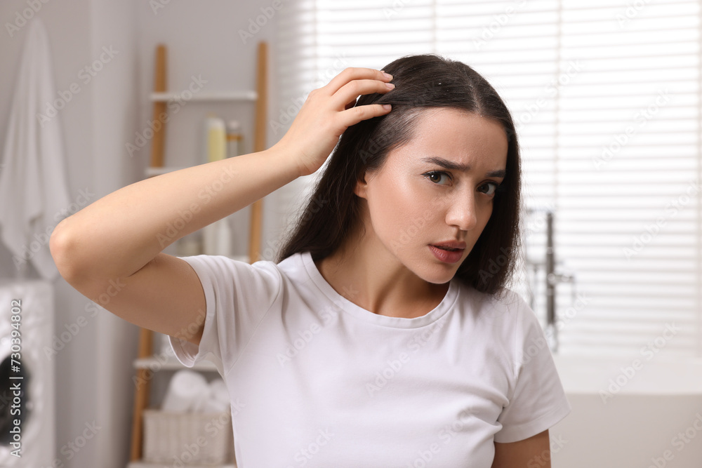 Emotional woman examining her hair and scalp in bathroom. Dandruff problem Emotional woman examining her hair and scalp in bathroom. Dandruff problem