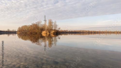Winter landscape without snow  the surface of the river Desenka with reflecting clouds  trees  the beautiful sky and reflection  the distant horizon  nature of Ukraine
