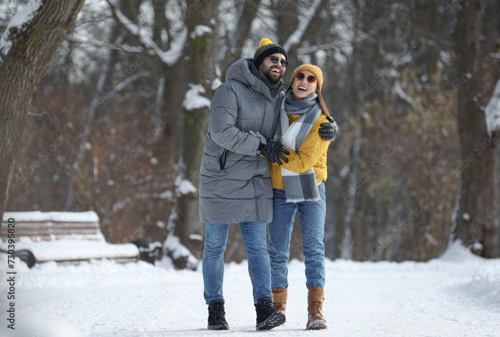 Happy young couple walking in snowy park on winter day Happy young couple walking in snowy park on winter day