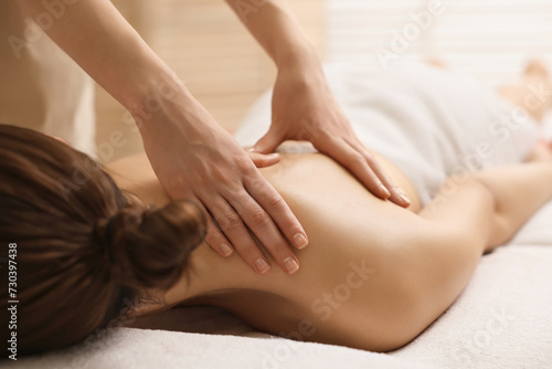 Woman receiving back massage on couch in spa salon, closeup