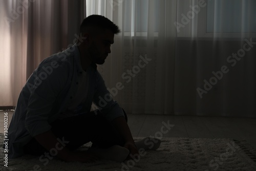 Silhouette of sad man in dark room. Space for text