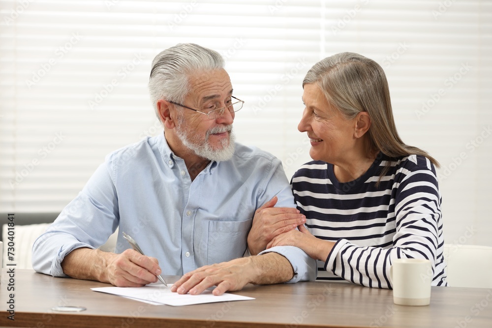 Senior couple signing Last Will and Testament indoors Senior couple signing Last Will and Testament indoors