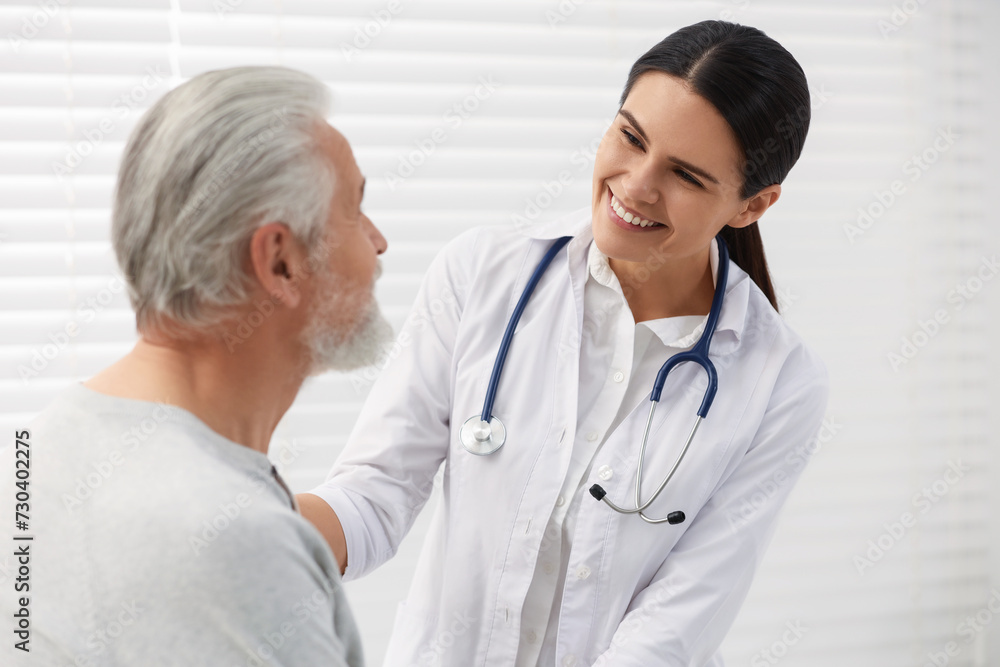 Smiling nurse supporting elderly patient in hospital Smiling nurse supporting elderly patient in hospital