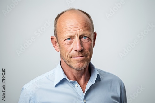 Portrait of a senior man in a blue shirt on a gray background.