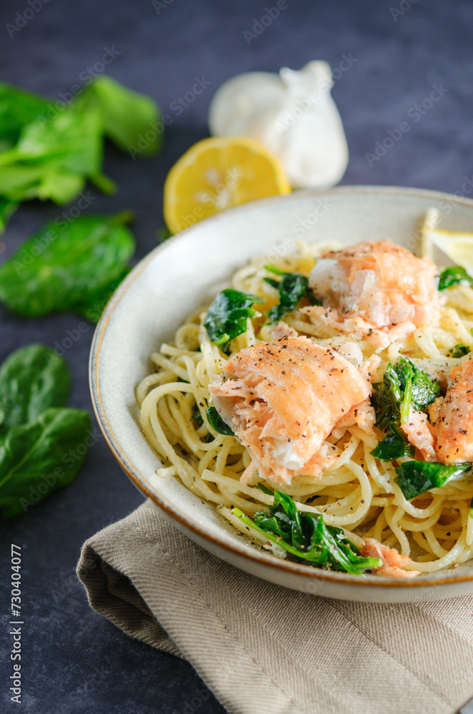 Italian cuisine: spaghetti with salmon, cream and spinach close-up on plate on table. vertical close up Italian cuisine: spaghetti with salmon, cream and spinach close-up on plate on table. vertical close up