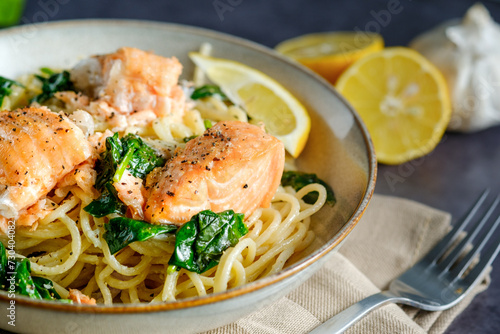 Italian cuisine: spaghetti with salmon, cream and spinach close-up on plate on table. horizontal close-up
