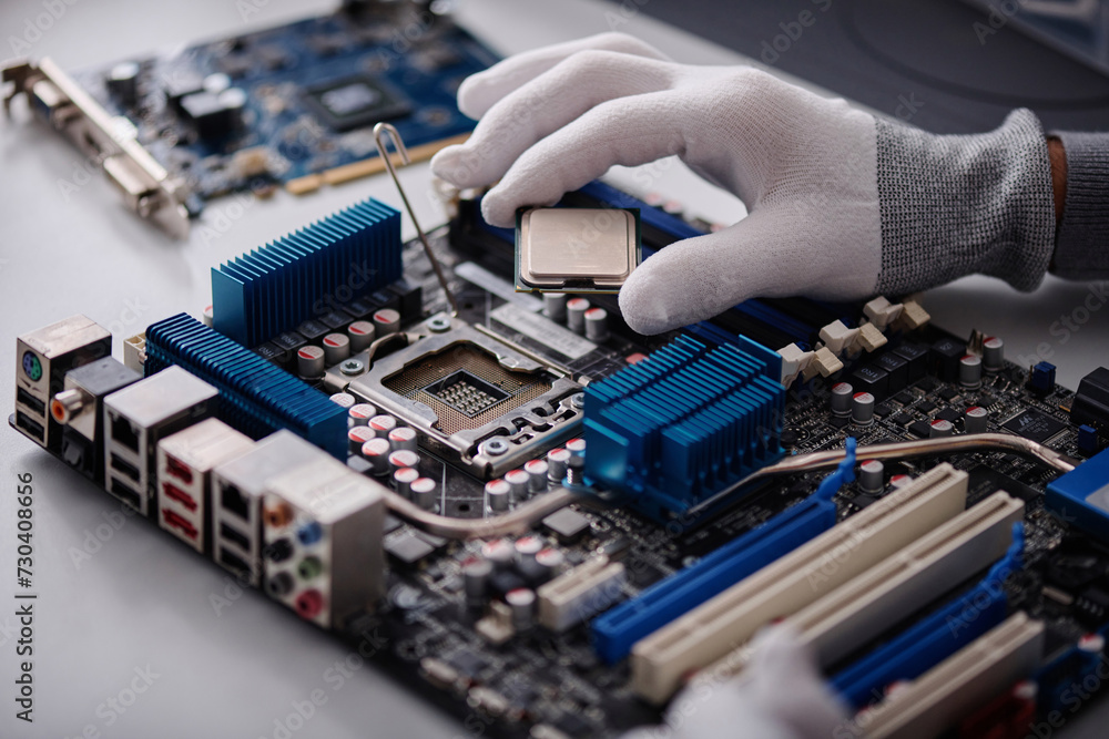 Hand of unrecognizable repairman inserting CPU into motherboard socket of disassembled computer Hand of unrecognizable repairman inserting CPU into motherboard socket of disassembled computer