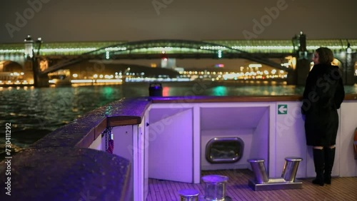 Woman stands on deck during vessel sails near bridge at evening in city photo