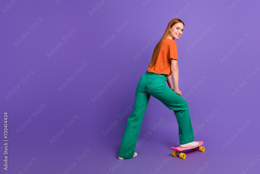 Full length photo of redhair student girl riding mini skateboard near empty space sports equipment shop isolated on purple color background