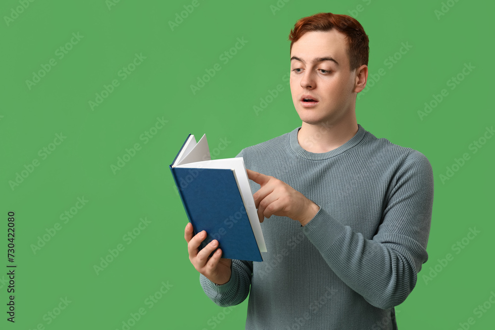 Young handsome man reading book on green background Young handsome man reading book on green background