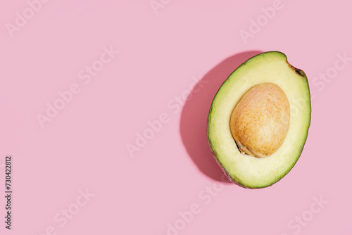Half of fresh ripe avocado on pink background