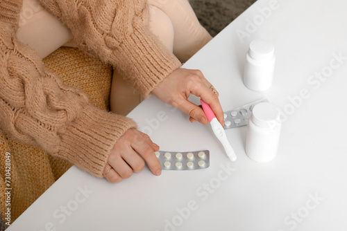 Woman with pregnancy test and pills on table at home  closeup