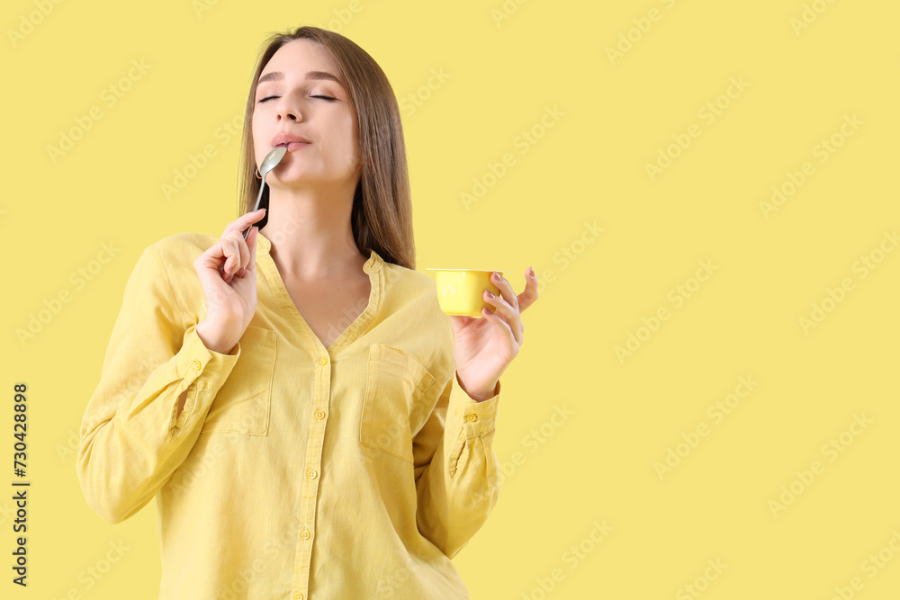 Young woman eating tasty yoghurt on yellow background Young woman eating tasty yoghurt on yellow background