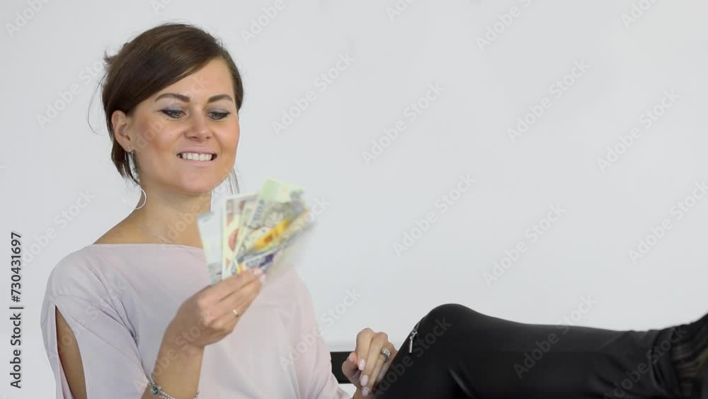 Smiling woman waves banknotes with her legs resting on table Smiling woman waves banknotes with her legs resting on table