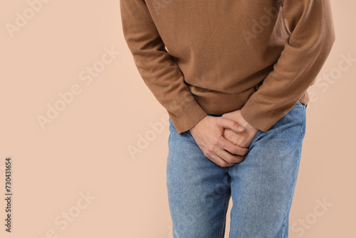 Young man with prostate problem on beige background, closeup. Cancer awareness concept