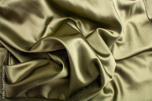 Green satin fabric background. View from above