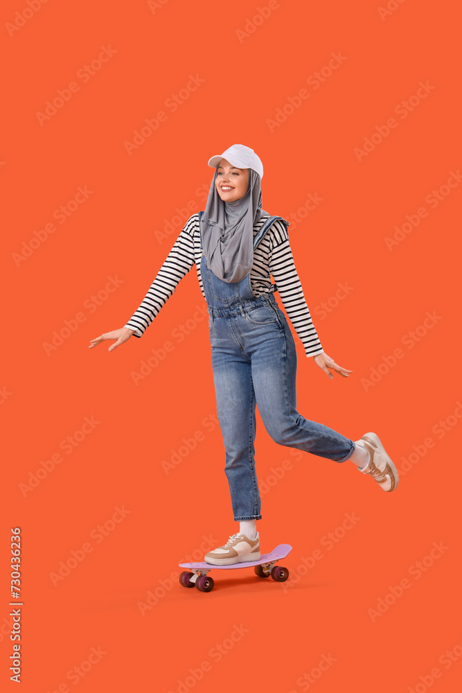Young Muslim woman in hijab skating on orange background Young Muslim woman in hijab skating on orange background