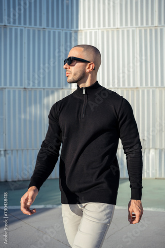 Hombre musculoso con ropa urbana posando en la calle