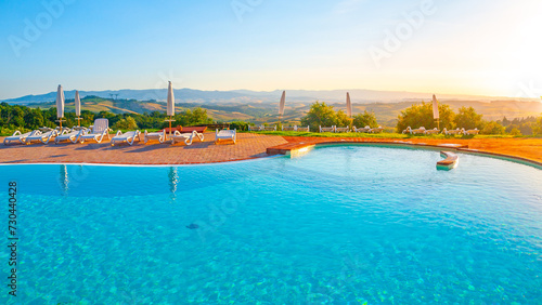 Blue swimming pool and beautiful hilly panoramic landscape at sunset time