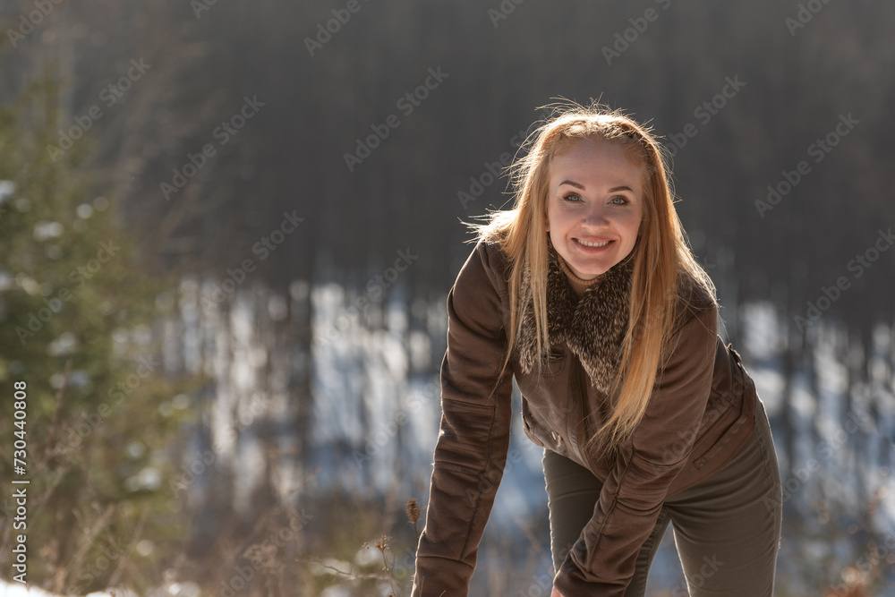 Portrait of smiling young woman with long hair outside in nature. Walk on sunny winter day. Portrait of smiling young woman with long hair outside in nature. Walk on sunny winter day.