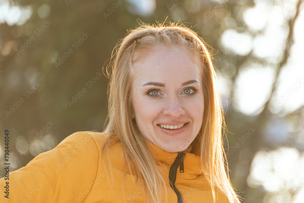 Close up portrait of smiling young woman with red hair in yellow jacket on sunny day. Warm light. Close up portrait of smiling young woman with red hair in yellow jacket on sunny day. Warm light.