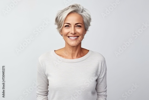 portrait of a beautiful middle aged woman smiling at the camera on grey background