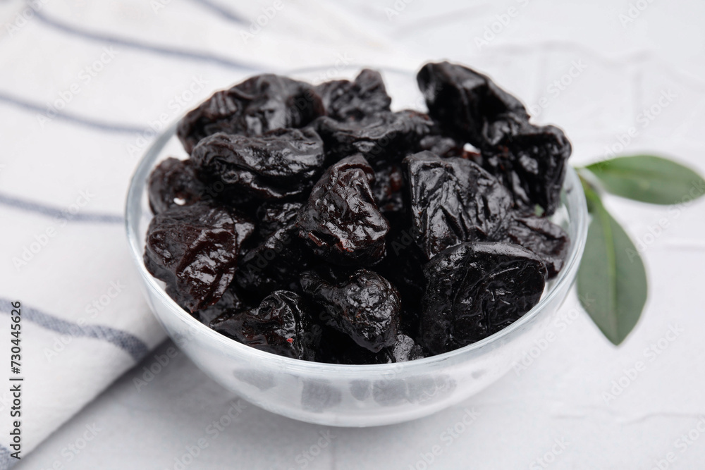 Sweet dried prunes in bowl on light table, closeup Sweet dried prunes in bowl on light table, closeup