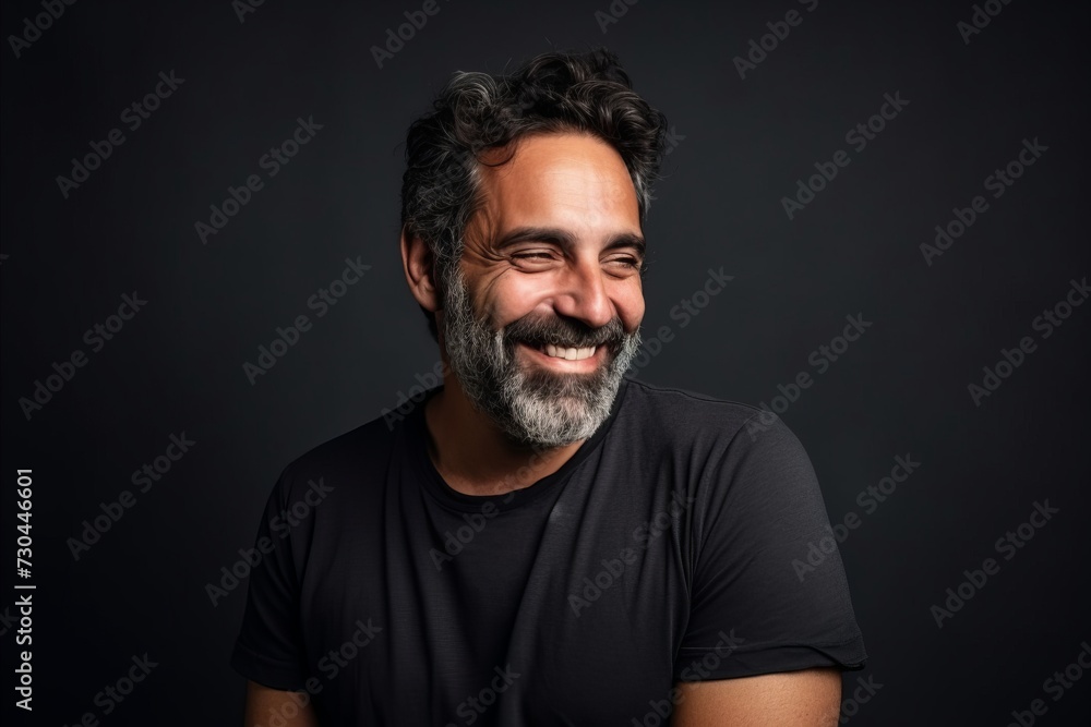 Portrait of a handsome bearded Indian man smiling on a dark background