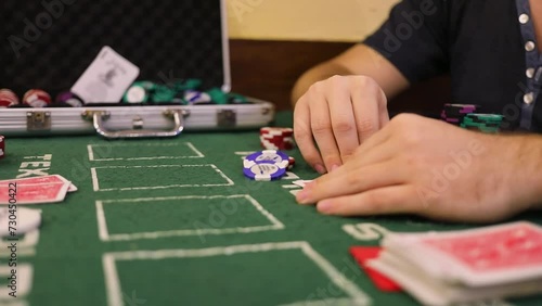 Man holds hands on cards during poker game on table with chips photo