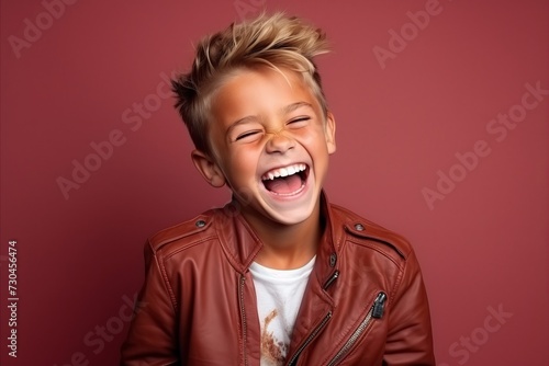 Portrait of a cute little boy in a brown leather jacket over dark background.