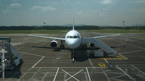 A grounded charter airplane at the airport terminal ready to board passengers. Front view of a white modern commercial aircraft which ready to fly to distant places from an international airport. photo