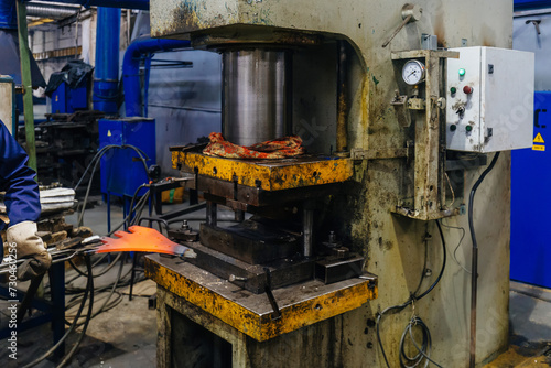 Worker puts iron hot part into press for pressing and quenching