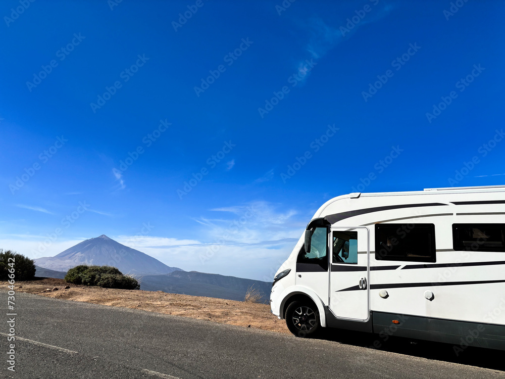 Modern motorhome camper van rv vehicle parking in the outdoors nature park with high mountain in background. Concept of travel and alternative vanlife house vacation. Freedom life and holiday