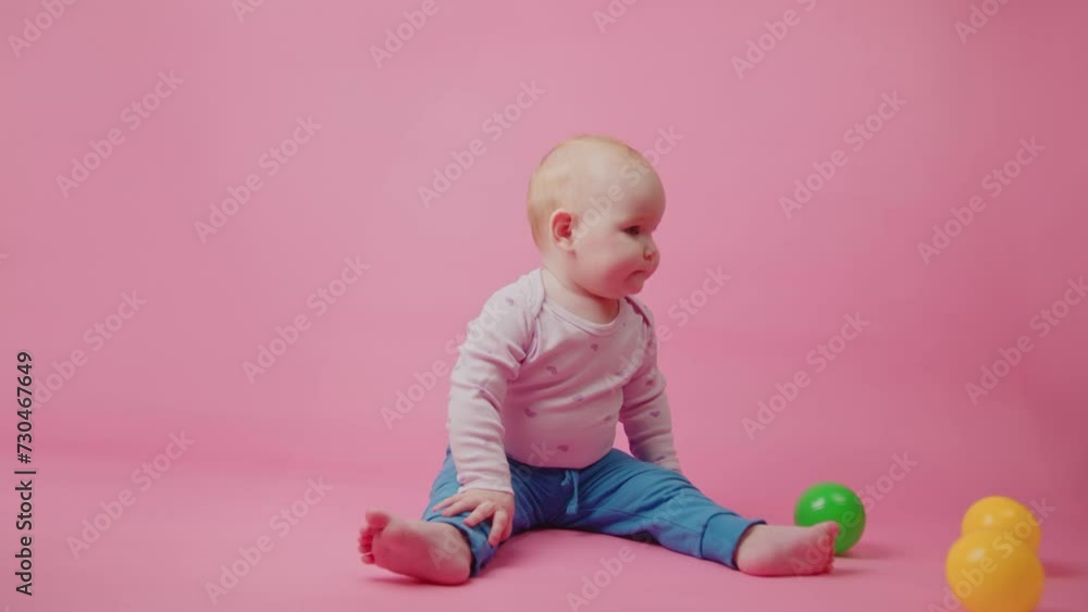 Cute little baby girl playing with colorful toy balls on pink background Cute little baby girl playing with colorful toy balls on pink background