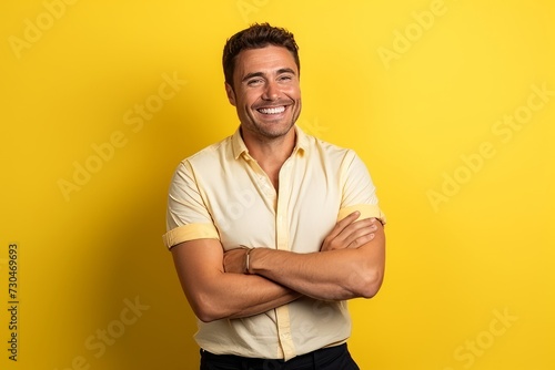 Portrait of a handsome young man with arms crossed on yellow background