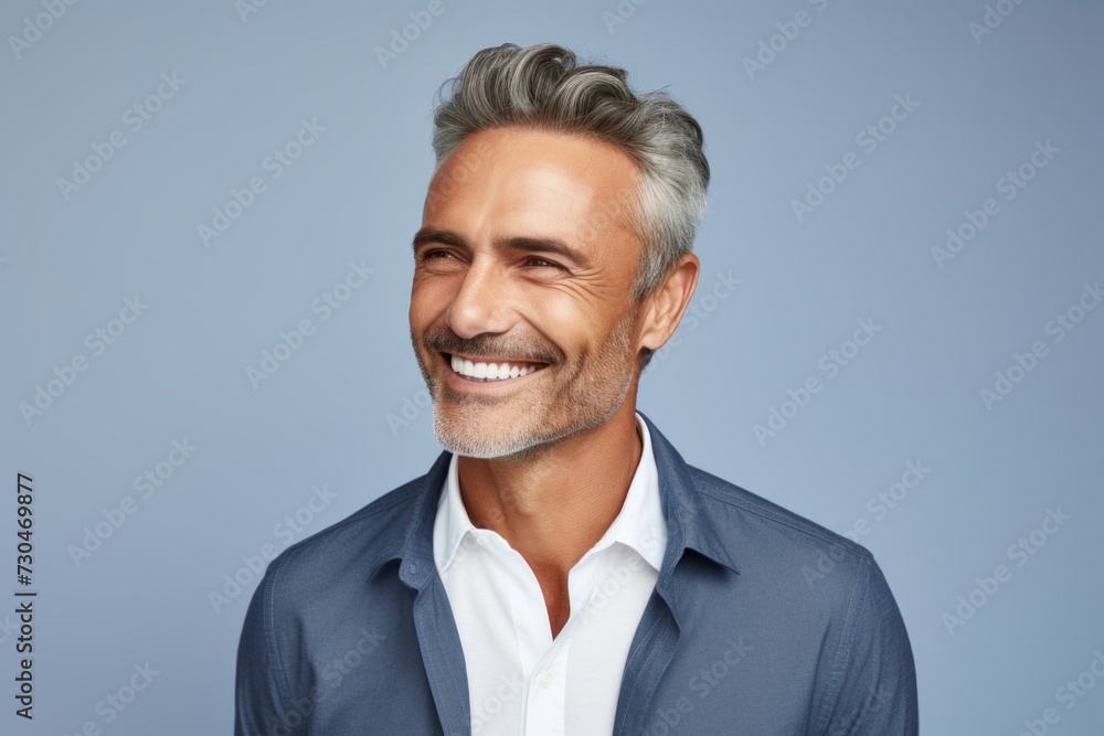 Portrait of handsome mature man smiling and looking at camera against blue background Portrait of handsome mature man smiling and looking at camera against blue background
