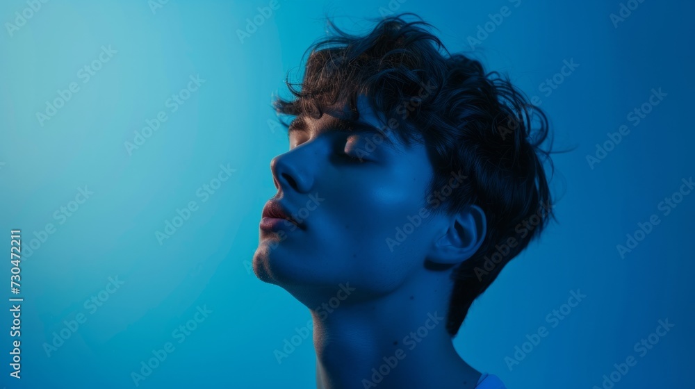 young man in a contemplative pose, surrounded by a cool blue background, generative ai young man in a contemplative pose, surrounded by a cool blue background, generative ai
