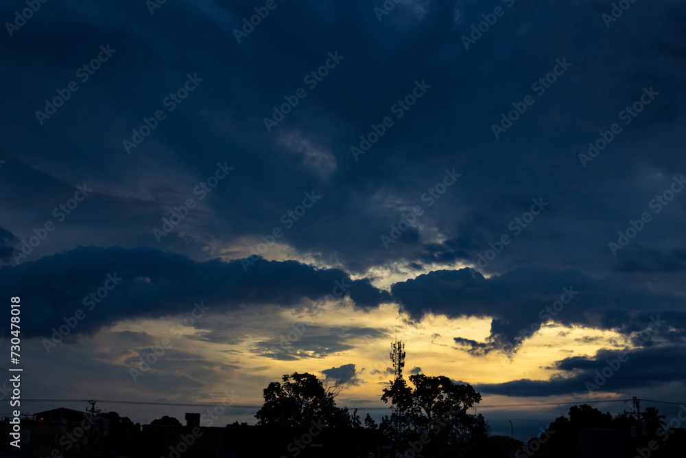 Sunset in the city, dramatic sky with clouds and silhouette of trees