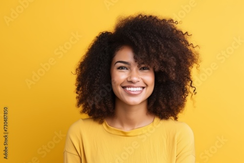 Portrait of a beautiful african american woman smiling over yellow background © Loli